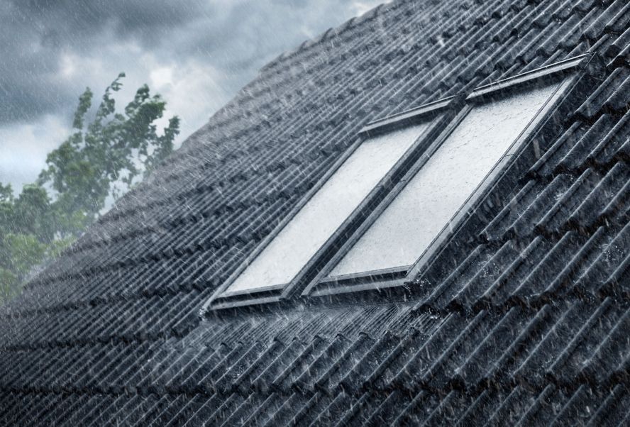Zwei, in einem schwarzen Ziegeldach eingebauten VELUX Dachfenster im Regen.
