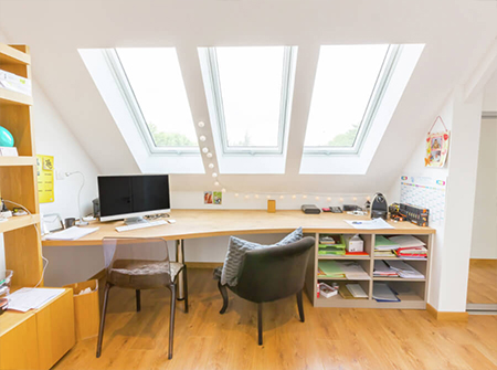 Ein helles Home Office mit drei langen VELUX Dachfenstern über dem Schreibtischbereich.