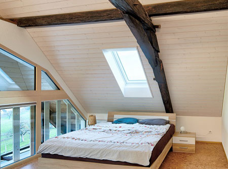 Une chambre aux éléments sombres dispose de trois longues fenêtres de toit VELUX