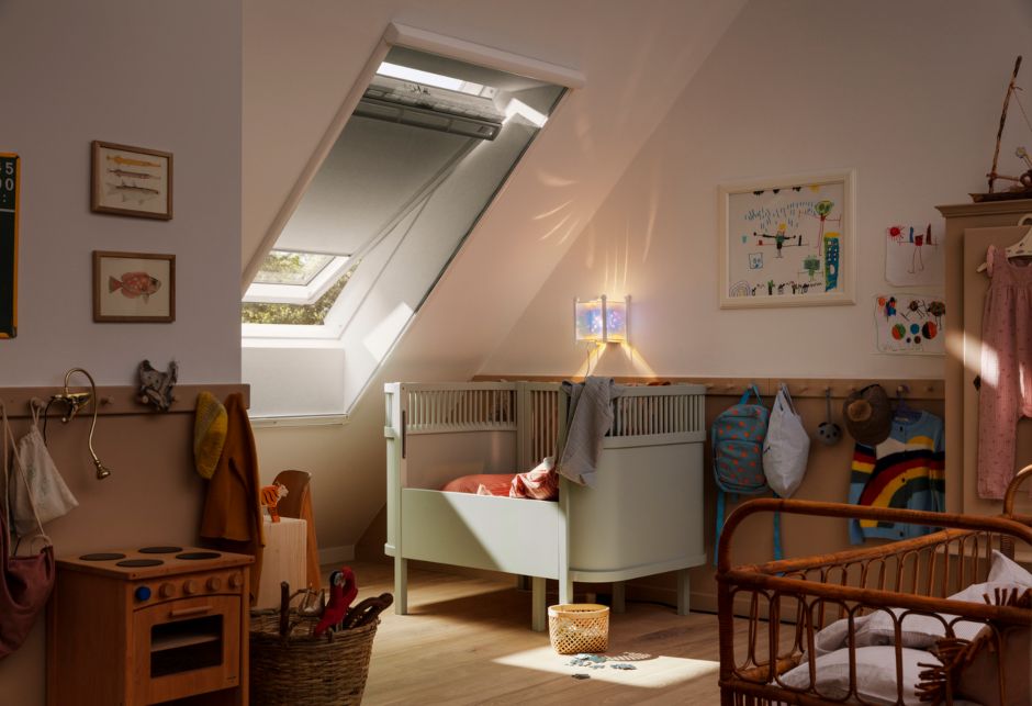 Ein Babyzimmer mit Bett und Spielzeug ist mit einem VELUX Dachfenster und Verdunkelungsrollo vor Tageslicht geschützt.