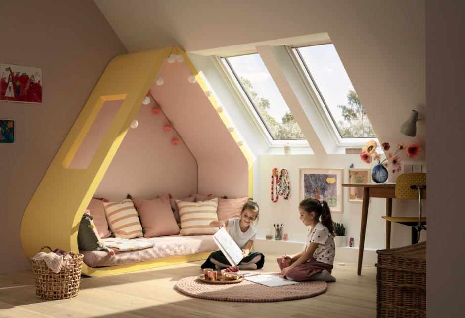Zwei Kinder spielen in einem hellen Kinderzimmer mit zwei VELUX Dachfenstern.